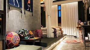 Et moderne hotelværelse med en sofa, et lille bord med en lampe og en dekorativ måtte.