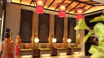 A traditional interior with decorative lanterns, a patterned wall, and a reception area with a counter and seating.