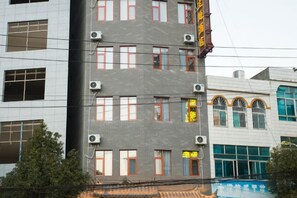 A multi-story building with air conditioning units, a swimming pool, and a traditional tiled roof. - Yixunli Theme Hotel (Luoping)