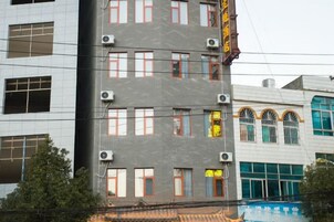 Un edificio de varios pisos con aires acondicionados, piscina y tejado de tejas tradicionales.
