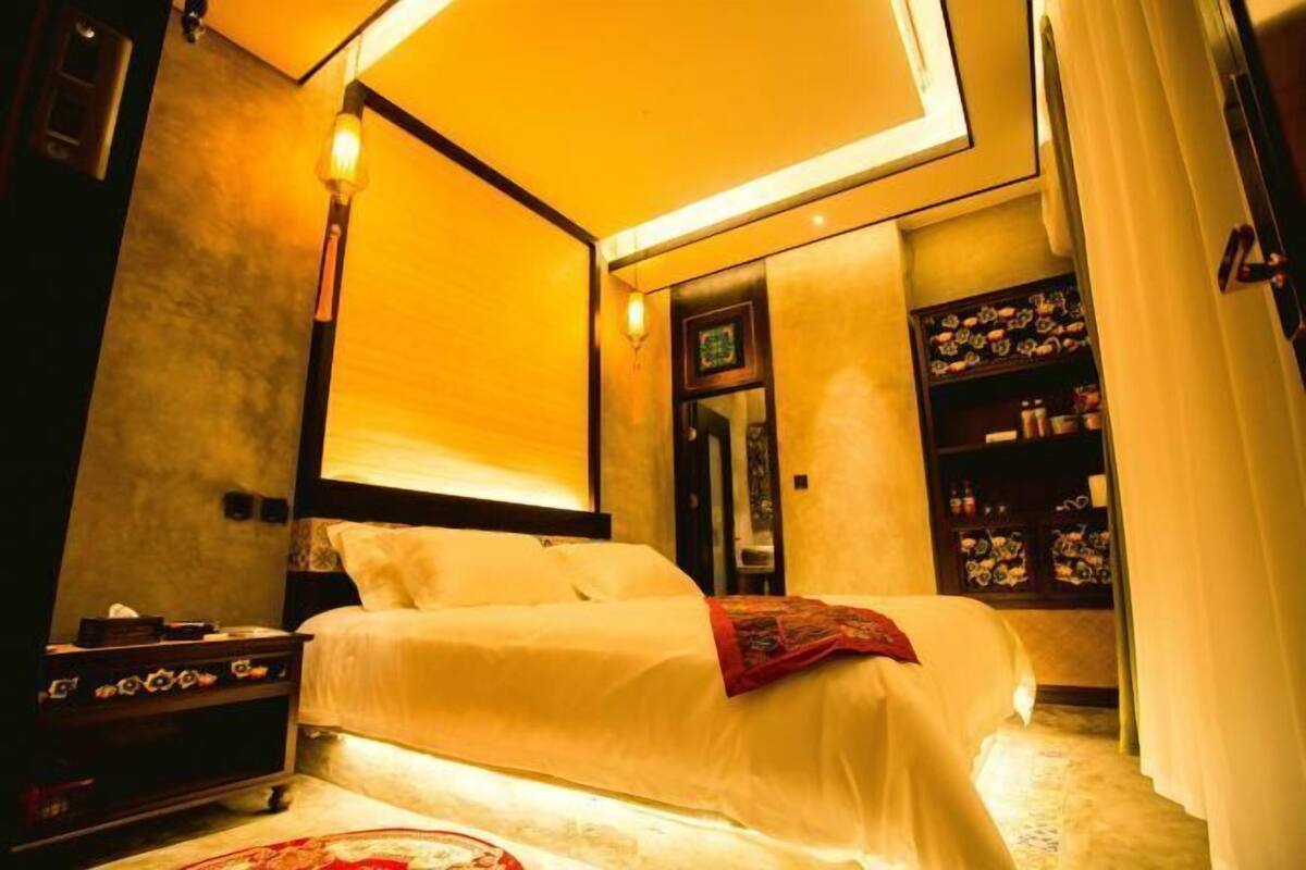 Ein Hotelzimmer mit Bett, Nachttisch, Lampe und einem Regal mit Dekoration.