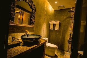 Un baño con un espejo grande, un lavamanos, un inodoro y una zona de ducha.