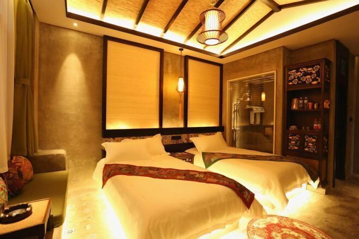 Ein Hotelzimmer mit zwei Betten, einer Holzbalkendecke und einem Bücherregal mit Dekoration.