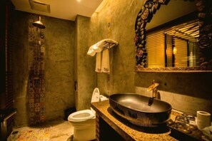 Un baño con un lavamanos grande y redondo, un inodoro y una zona de ducha.