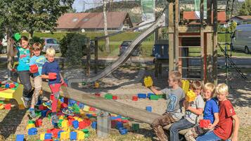 Kinder spielen mit Bauklötzen in der Nähe einer Spielgeräte-Anlage.