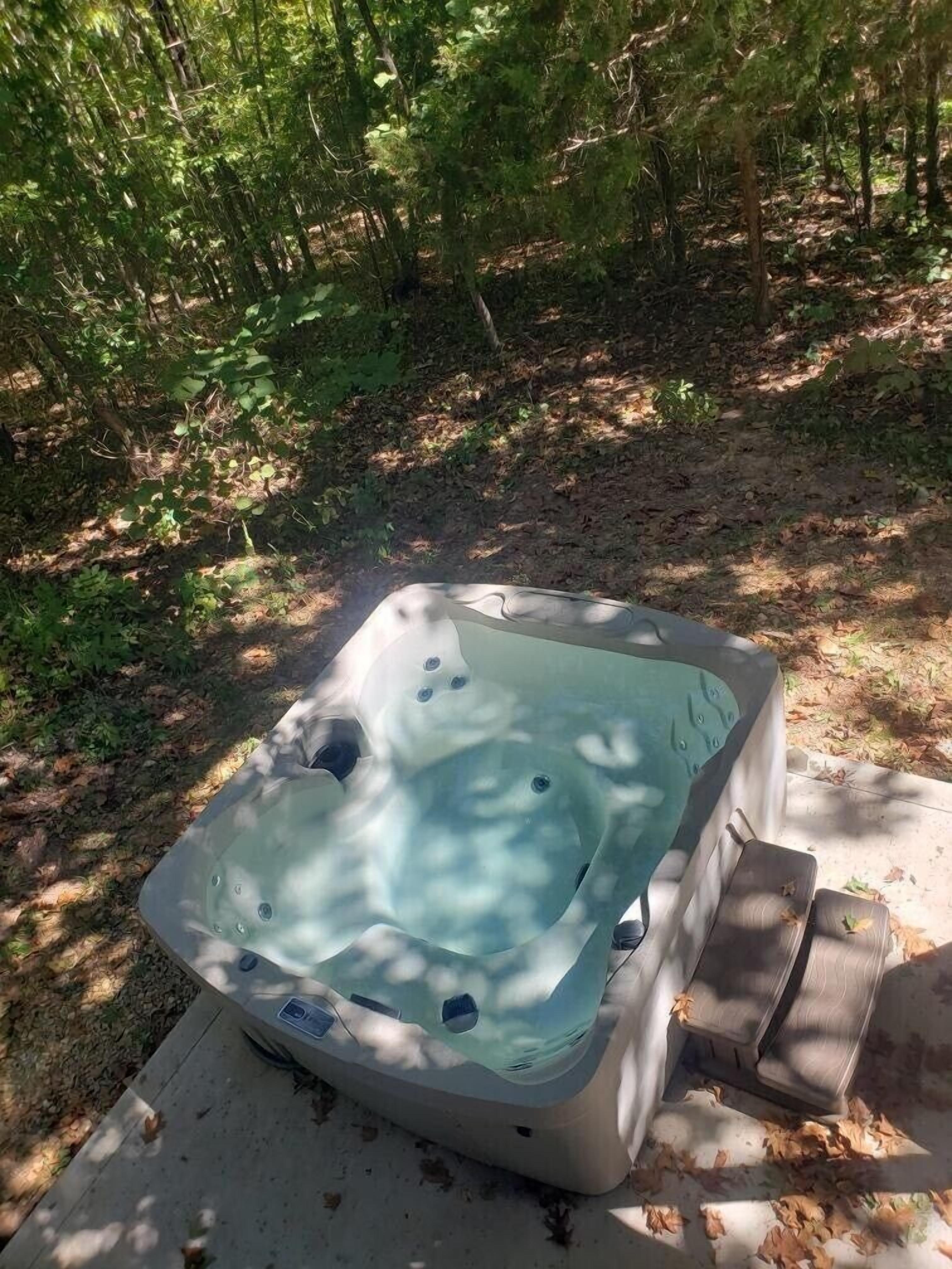 A hot tub in a wooded area with a concrete platform.
