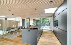 Enjoy meals in the spacious kitchen and dining area, featuring a central island, oven, and modern dining table.