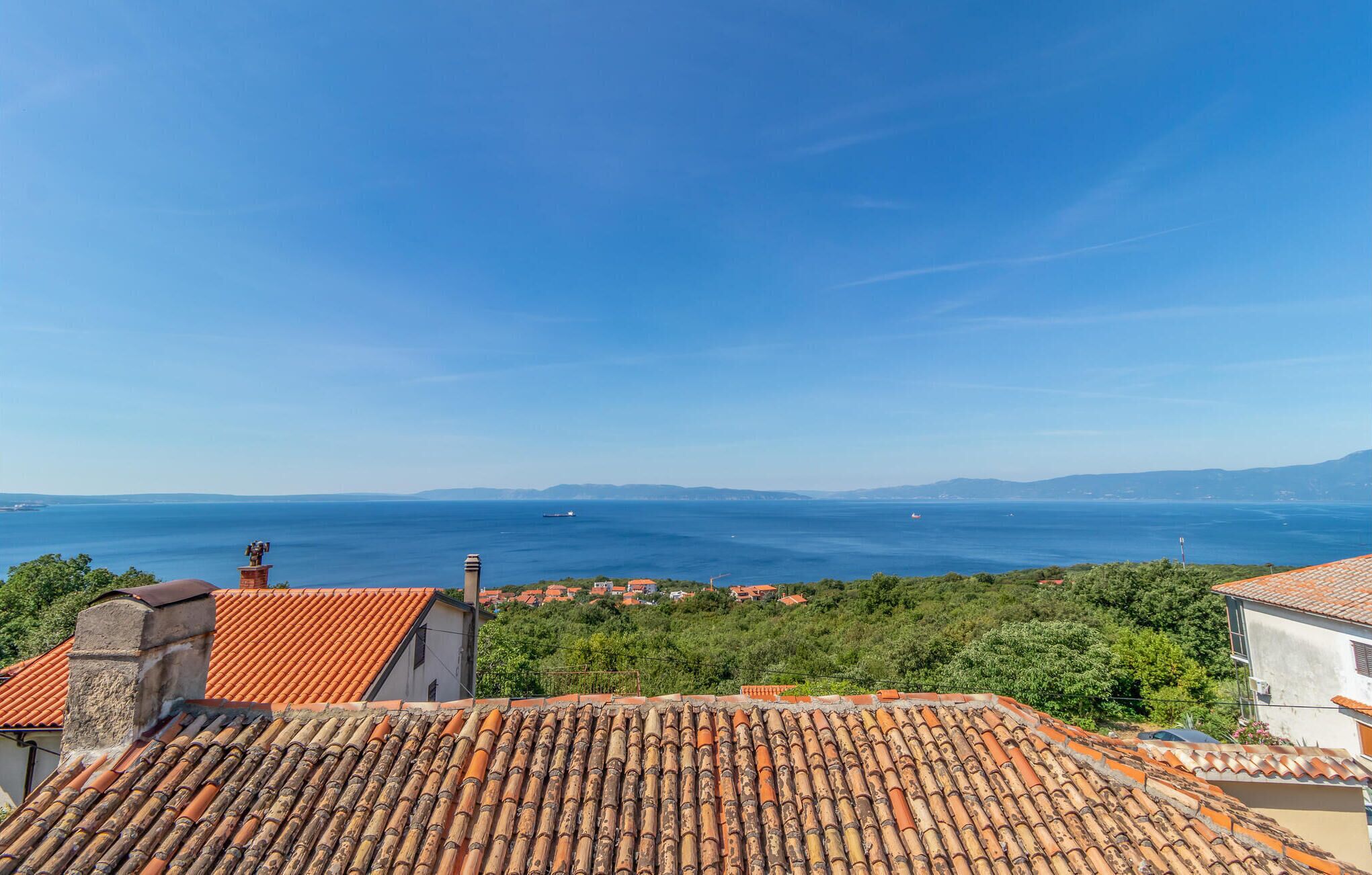 A coastal town with terracotta rooftops, a clear blue sky, and a view of the sea.