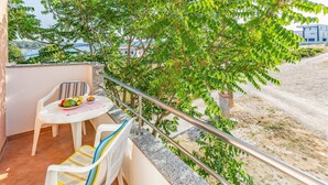 A balcony with a table, chairs, and a railing overlooking a beach and buildings. - 2 bedroom amazing apartment in Medulin (Medulin)