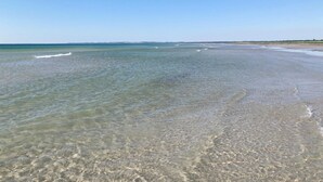 Una playa con aguas cristalinas y poco profundas y una costa distante.