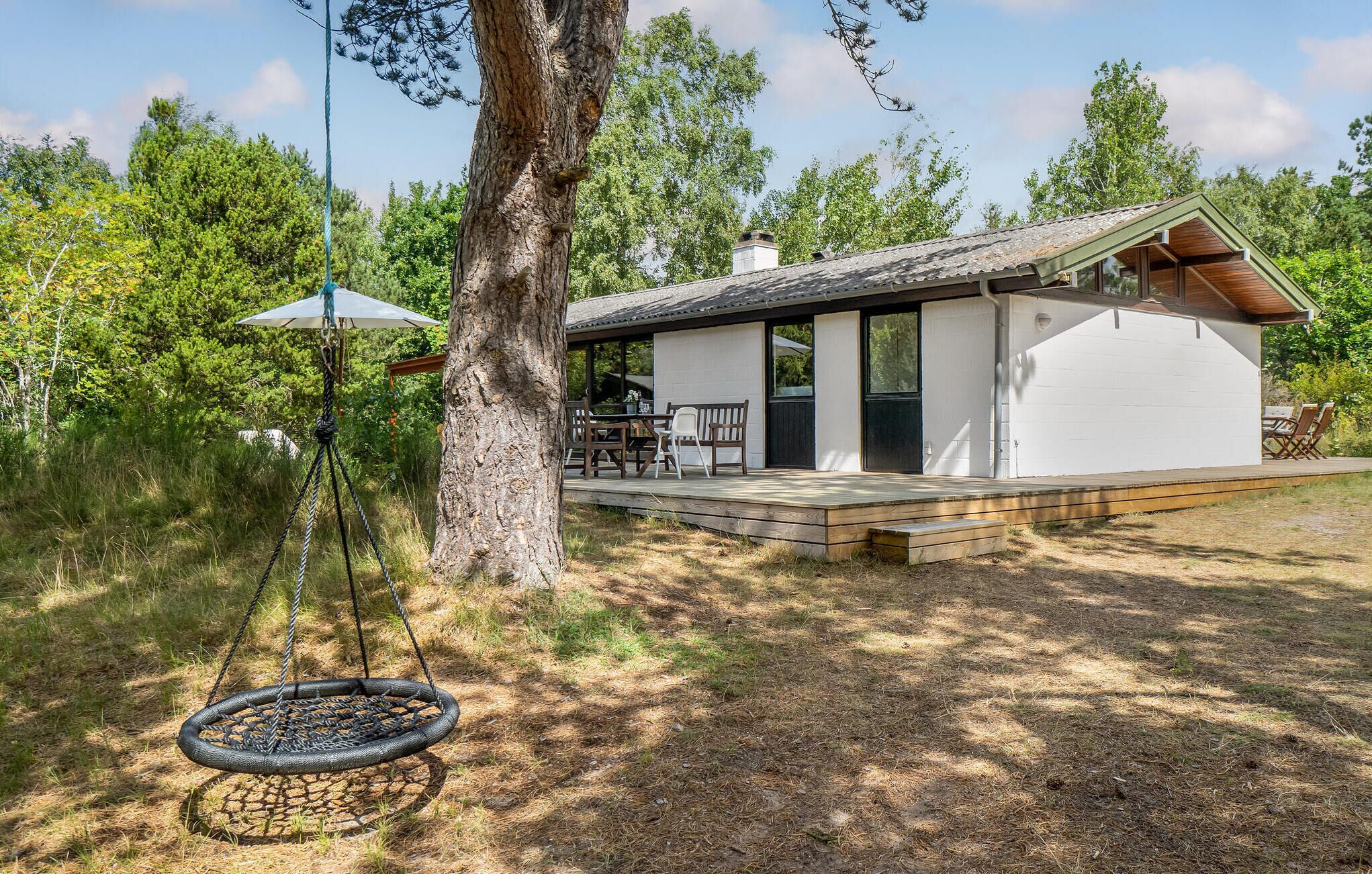 A modern house with a deck, a swing, and a patio area.