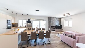 A modern kitchen with a dining area, a living room with a pink sofa, and a fireplace. - Beautiful home in Trogir (Trogir)