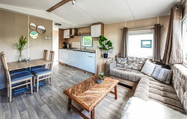 Ett kompakt bostadsutrymme med en matplats, en soffa, ett soffbord och ett litet kök.
