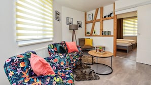 Un salon moderne avec un canapé à motifs floraux, une petite table ronde et une bibliothèque en bois.