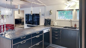 A modern kitchen with dark cabinetry, a built-in dishwasher, and a large window with a view of greenery. - 3 bedroom cozy home in Skjern (Skjern)