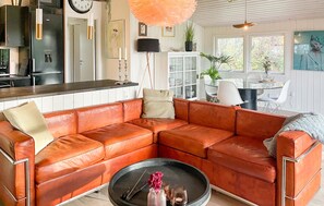A modern living room with a leather sectional sofa, a round coffee table, and a dining area with a glass table and chairs.