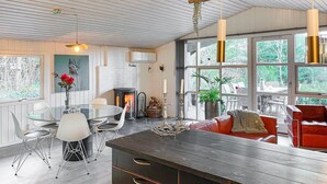A modern kitchen with a central island, dining area with chairs, and a red sofa. - 3 bedroom cozy home in Skjern (Skjern)
