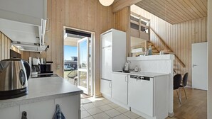 A compact kitchen with white cabinets, a coffee machine, and a sink.