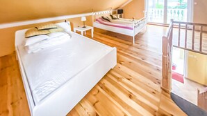A bedroom with a large bed, a nightstand, a lamp, and a view of the outdoors through a window. - Awesome home in Kamionki Male (Kamionki Male)