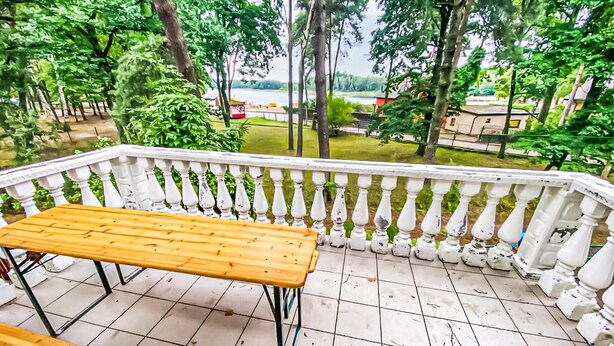 A balcony with a wooden table, white balustrade, and a view of a park and buildings. - Awesome home in Kamionki Male (Kamionki Male)