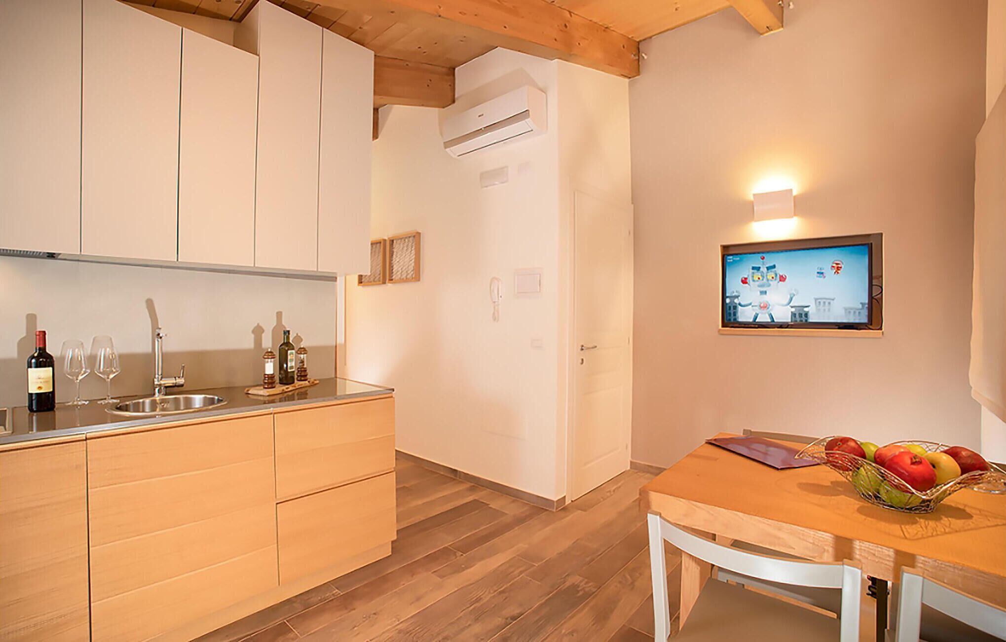 A kitchen with wooden cabinets, a sink, and a dining area with a table and chairs.
