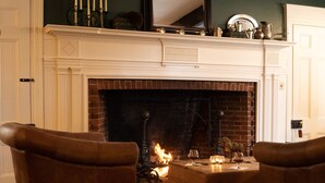 A cozy living room with a fireplace, leather armchairs, and a coffee table. - OneSixtyFive (Brunswick)