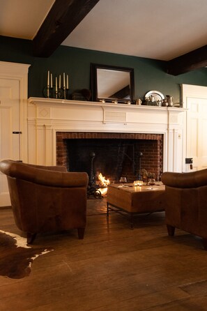 A cozy living room with a fireplace, leather armchairs, and a coffee table. - OneSixtyFive (Brunswick)