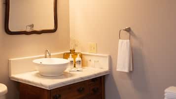A bathroom with a white sink, wooden vanity, and a mirror with three lights.