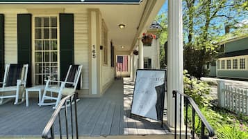 A porch with outdoor seating, a sign for PUB165, and a view of a building with a green facade.