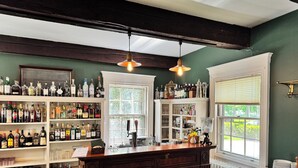 A bar area with shelves of liquor bottles, a bar counter, stools, and a radiator. - OneSixtyFive (Brunswick)