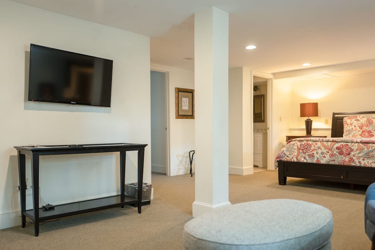 A bedroom with a bed, bedside lamp, and a television on the wall.