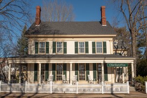 A two-story building with a white picket fence, green shutters, and a sign reading "OneSixtyFive."