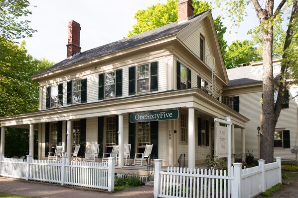 A two-story building with a porch, white picket fence, and a sign reading "OneSixtyFive".
