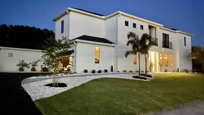 A modern two-story house with a white exterior, a driveway, and a well-maintained lawn. - Intimate Heated Pool Side Beach Bungalow! Just steps to the beach! (St. Augustine)