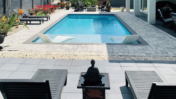 A swimming pool with lounge chairs, a statue, and a building with a balcony. - Intimate Heated Pool Side Beach Bungalow! Just steps to the beach! (St. Augustine)