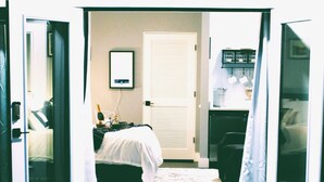A hotel room with a bed, a desk, a chair, a wardrobe, and a small kitchen area. - Intimate Heated Pool Side Beach Bungalow! Just steps to the beach! (St. Augustine)