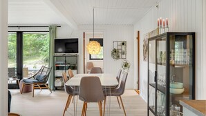 A modern dining area with a white table and grey chairs, a television above the table, and a glass cabinet with dishes. - Awesome home in Ebeltoft with WiFi (Ebeltoft)