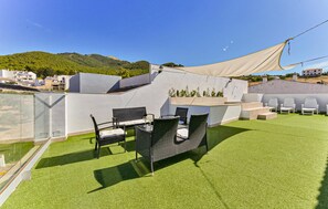 A rooftop terrace with artificial grass, outdoor seating, and a view of a hillside. - Lovely home in Montecorto (Montecorto)