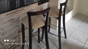 Une cuisine compacte avec un îlot central, un coin repas avec deux chaises et un tableau accroché au mur.