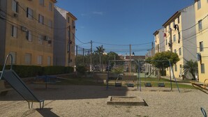 Un terrain de jeux avec des balançoires et un toboggan, entouré d’immeubles.