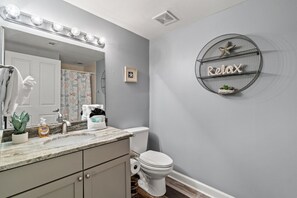 A bathroom with a vanity, a toilet, a sink with a mirror, and a wall-mounted shelf with a starfish and the word "Relax". - Beachfront 3rd Floor Great Views! Shores of Panama (Panama City Beach)