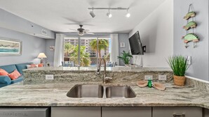 Una cucina moderna con un piano di lavoro in granito, lavello in acciaio inossidabile e una ventola a soffitto.