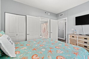 A bedroom with a bed, a dresser, a television, and a door leading to another room. - Beachfront 3rd Floor Great Views! Shores of Panama (Panama City Beach)