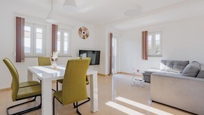 Ein modernes Wohnzimmer mit Essbereich, einer Couch und einem Fernseher.