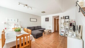 Ein modernes Wohnzimmer mit Essbereich, ausgestattet mit einer Couch, einem Esstisch mit Stühlen und einer Treppe zu einer weiteren Ebene.