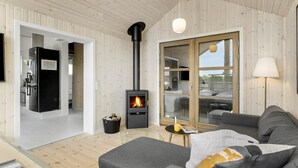 Ett modernt vardagsrum med en svart vedkamin, en grå soffa och ett trägolv.