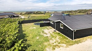 Ett bostadsområde med hus, en inhägnad trädgård och utsikt över havet.