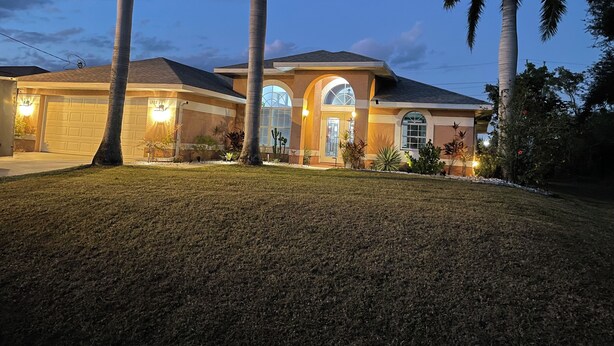 A two-story house with a garage, arched windows, and palm trees. - Pool home in a quiet neighborhood (Cape Coral)