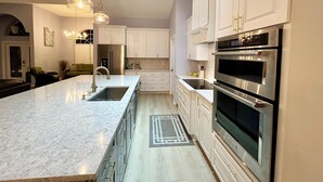 A modern kitchen with white cabinetry, stainless steel appliances, and pendant lighting. - Pool home in a quiet neighborhood (Cape Coral)