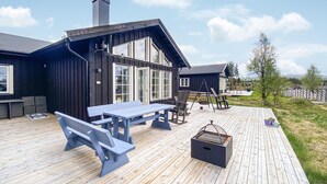 A wooden deck with a picnic table and benches, a hanging chair, and a barbecue grill. - 4 bedroom beautiful home in Tisleidalen (Tisleidalen)